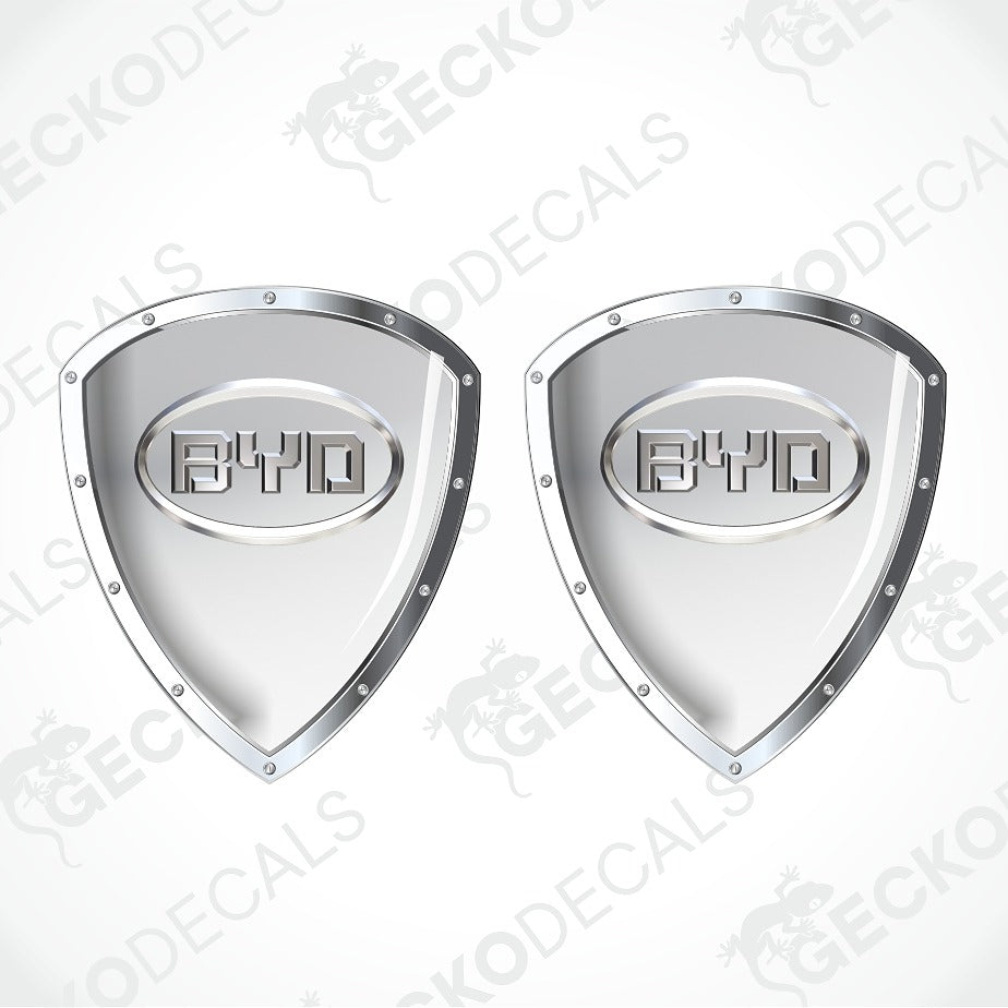Two identical metallic silver shield-shaped decals with a central oval logo reading BYD, shown on a light gray background with repeated watermark text.