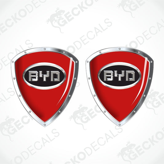 Two red shield-shaped BYD car decals with silver metallic borders and a black center containing the BYD logo, shown on a white background with faint watermarks.