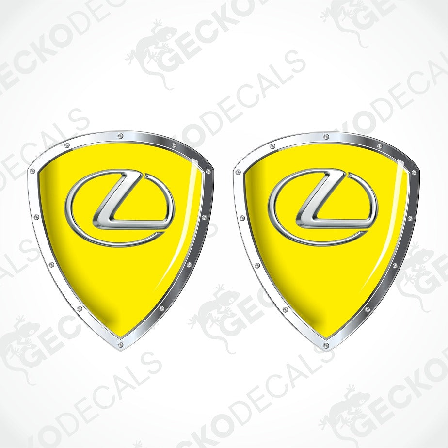 Two identical yellow shield-shaped decals with silver metallic borders and the Lexus logo in the center, shown on a white background with faint GECKODECALS watermarks.