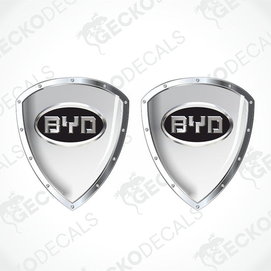 Two identical shield-shaped chrome car decals with a black center and the BYD logo, shown on a light gray background with a faint diagonal watermark.