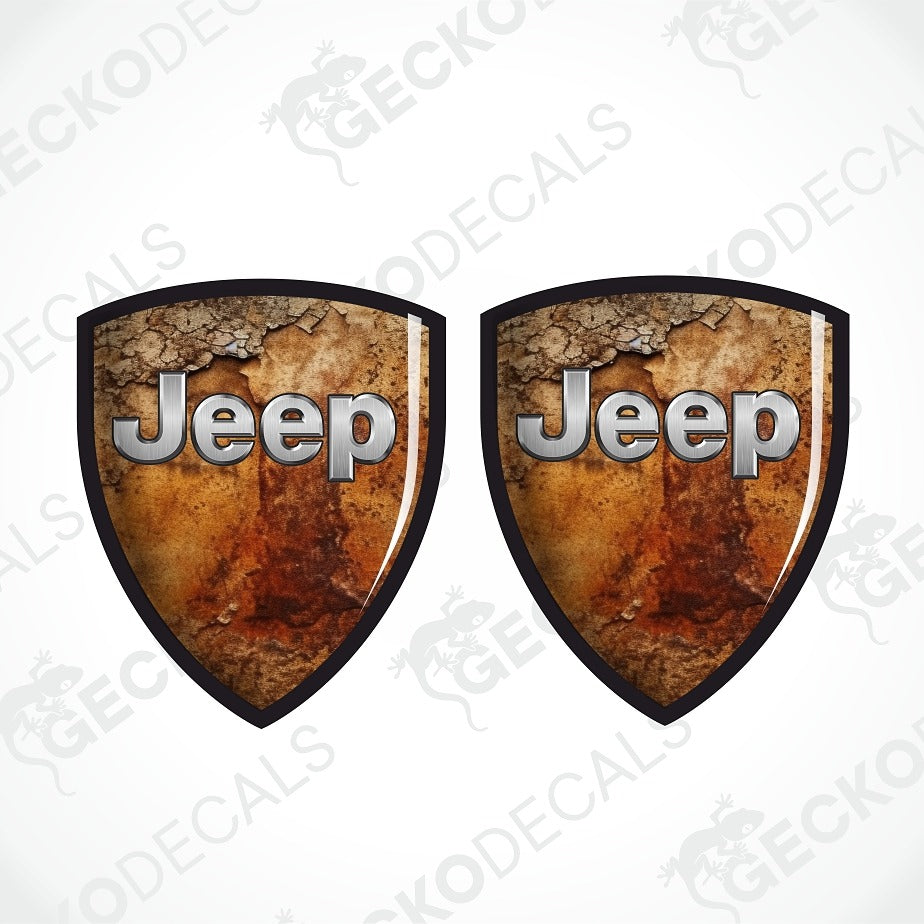 Two shield-shaped Jeep decals with a distressed brown and orange textured background and metallic silver 'Jeep' lettering, shown on a white background with a faint watermark pattern.