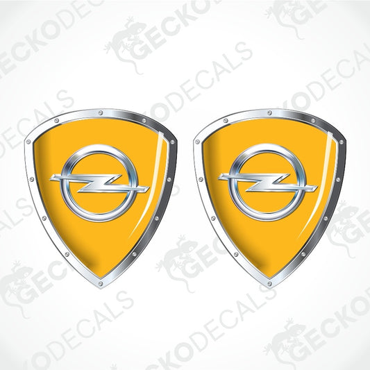 Two identical yellow car decals in the shape of shields with silver borders and the Opel logo in the center, shown on a light gray background with diagonal watermarks.