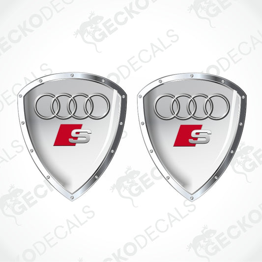 Two silver Audi S shield-shaped decals with the four-ring logo and red S badge, shown on a white background with diagonal watermark text.