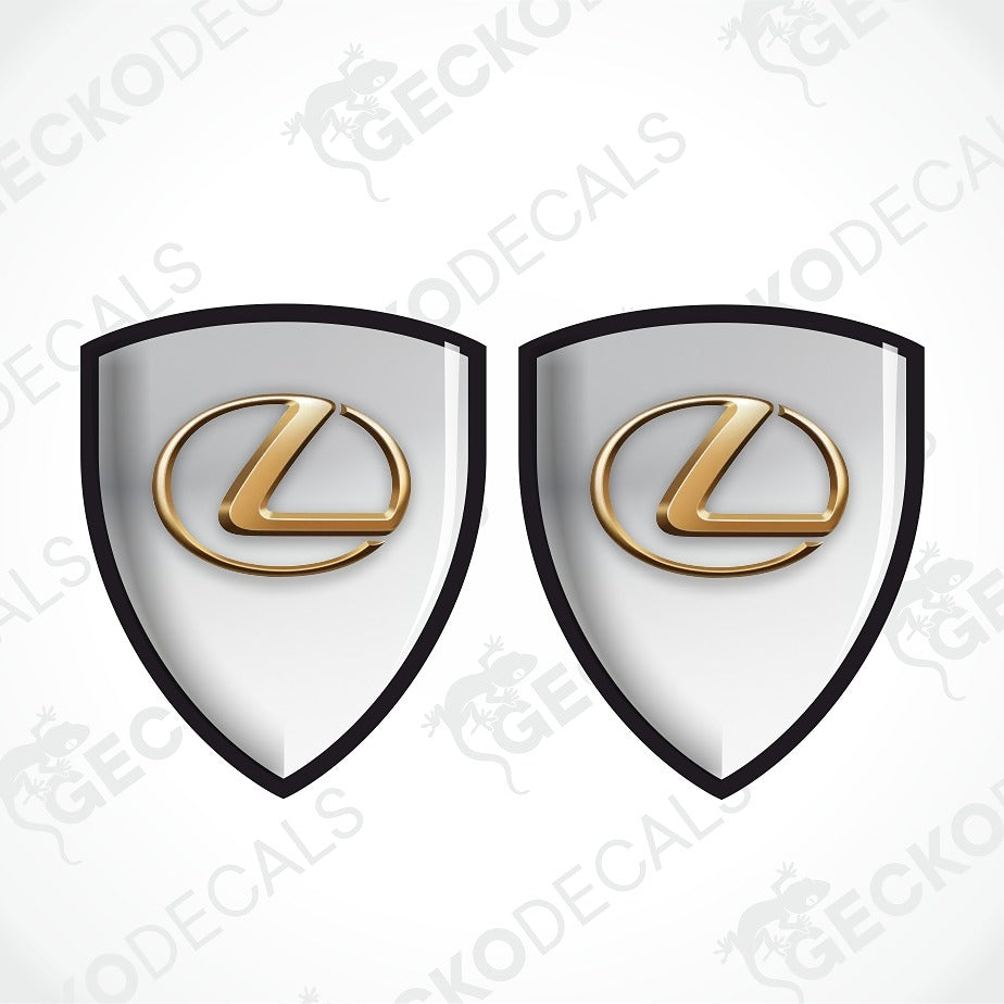 Two identical Lexus shield-shaped decals with a white center, black border, and a raised gold Lexus logo, shown on a light gray background with faint GECKODECALS watermarks.