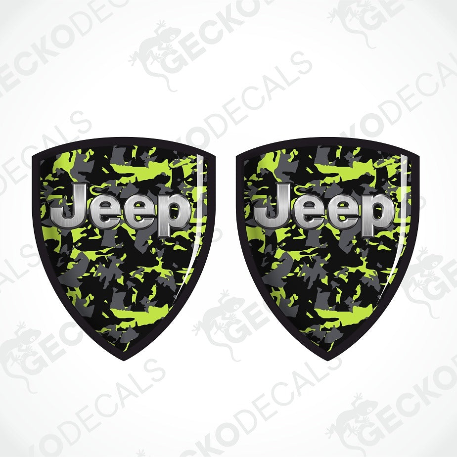 Two shield-shaped Jeep decals with a green, black, and gray camouflage pattern and silver 'Jeep' lettering, shown on a white background with diagonal watermarks.