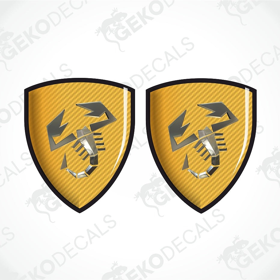 Two identical yellow carbon-fiber-textured shield decals with a black border and a stylized scorpion logo, shown on a white background with diagonal watermark text.