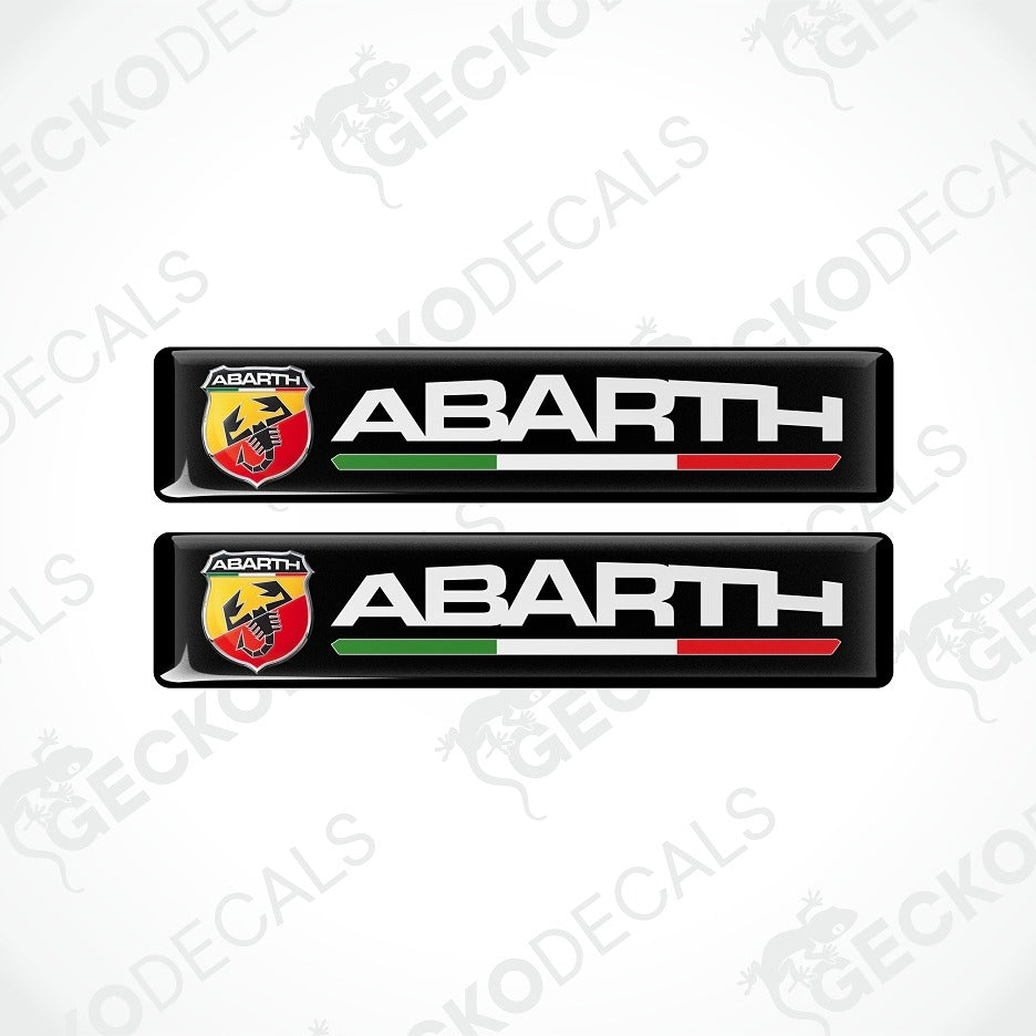 Two black Abarth car decal stickers on a light gray background with diagonal watermarks. Each sticker features the Abarth logo, the word 'ABARTH' in white, and a green, white, and red horizontal stripe.