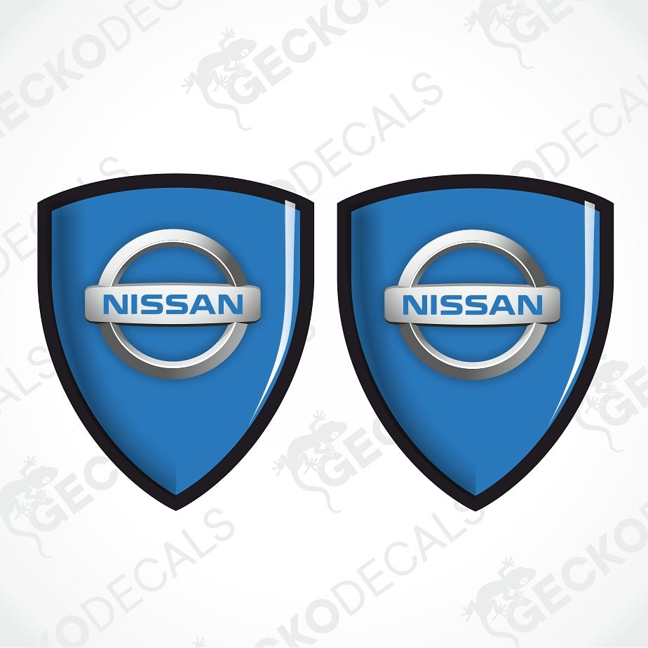 Two blue Nissan shield-shaped decals with the Nissan logo in the center, shown on a light gray background with faint GECKODECALS watermarks.