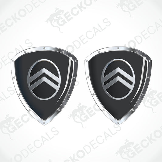 Two identical black and silver shield-shaped decals with a circular chevron emblem in the center, shown on a white background with a faint diagonal watermark pattern.