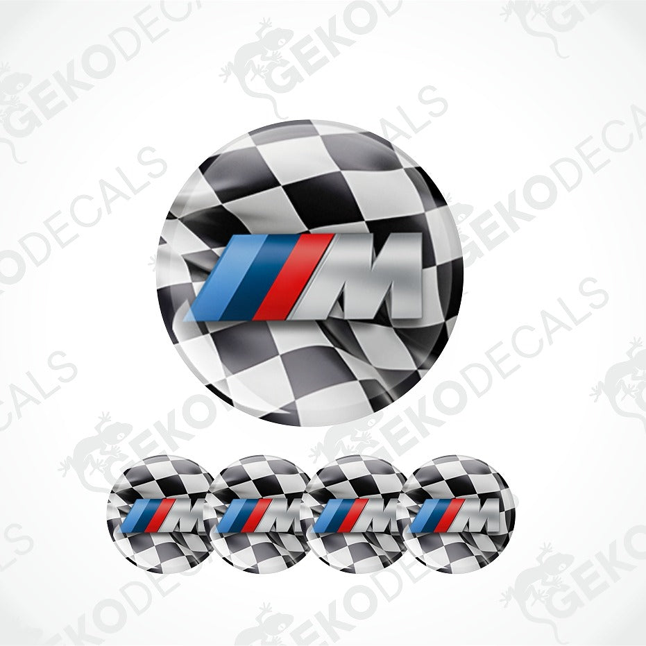 A set of circular decals featuring a black and white checkered pattern with a prominent silver 'M' logo accented by the classic blue and red stripes of the BMW M series. The main decal is shown large at the top, with four smaller versions aligned horizontally at the bottom against a white background with diagonal watermarks.