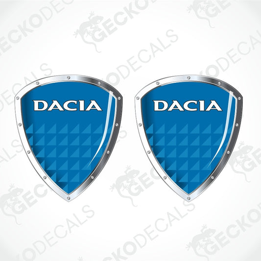 Two identical blue shield-shaped Dacia decals with silver borders and white lettering, shown on a light gray background with a faint watermark pattern.