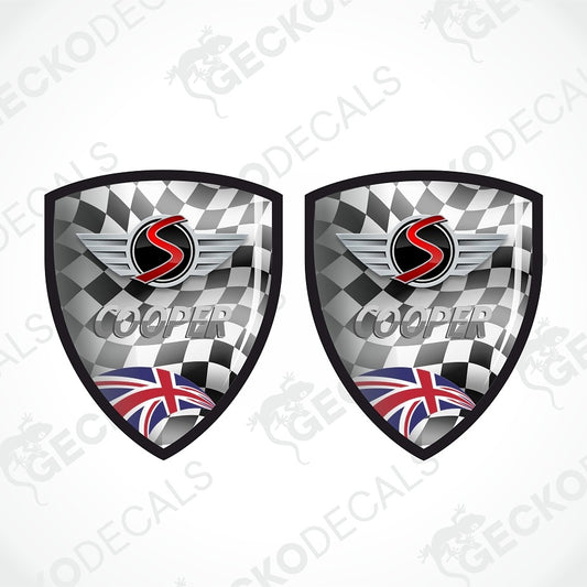 Two identical shield-shaped racing decals on a light gray background. Each decal features a black-and-white checkered flag pattern, a red and black winged 'S' logo, the word 'COOPER' in gray, and a Union Jack flag at the bottom.