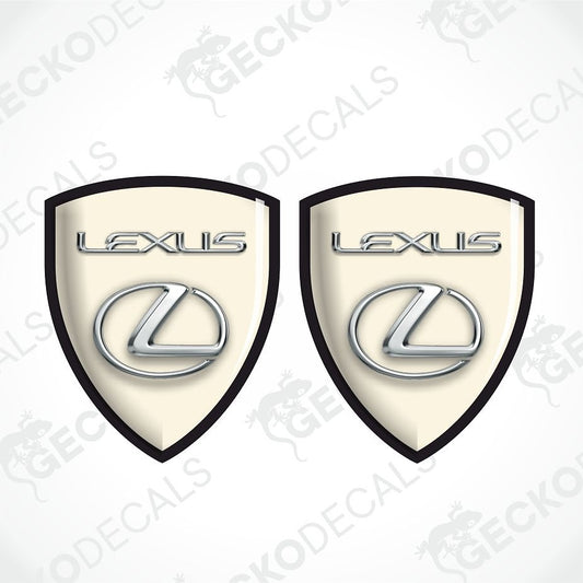 Two identical Lexus shield-shaped decals on a white background with diagonal watermarks. Each decal has a cream center, black border, silver Lexus wordmark, and silver Lexus logo.