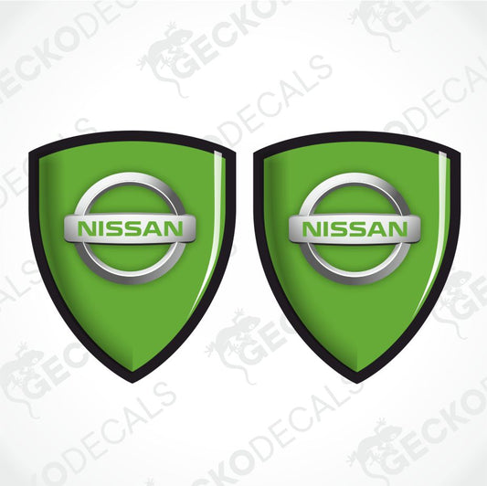 Two green Nissan shield-shaped decals with black borders and silver circular logos, shown on a light gray background with faint Geckodecals watermarks.
