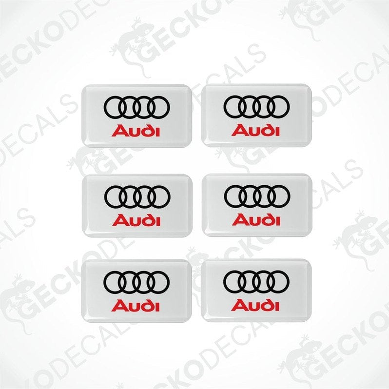 A set of six white vinyl stickers with a red and black Audi logo on each.