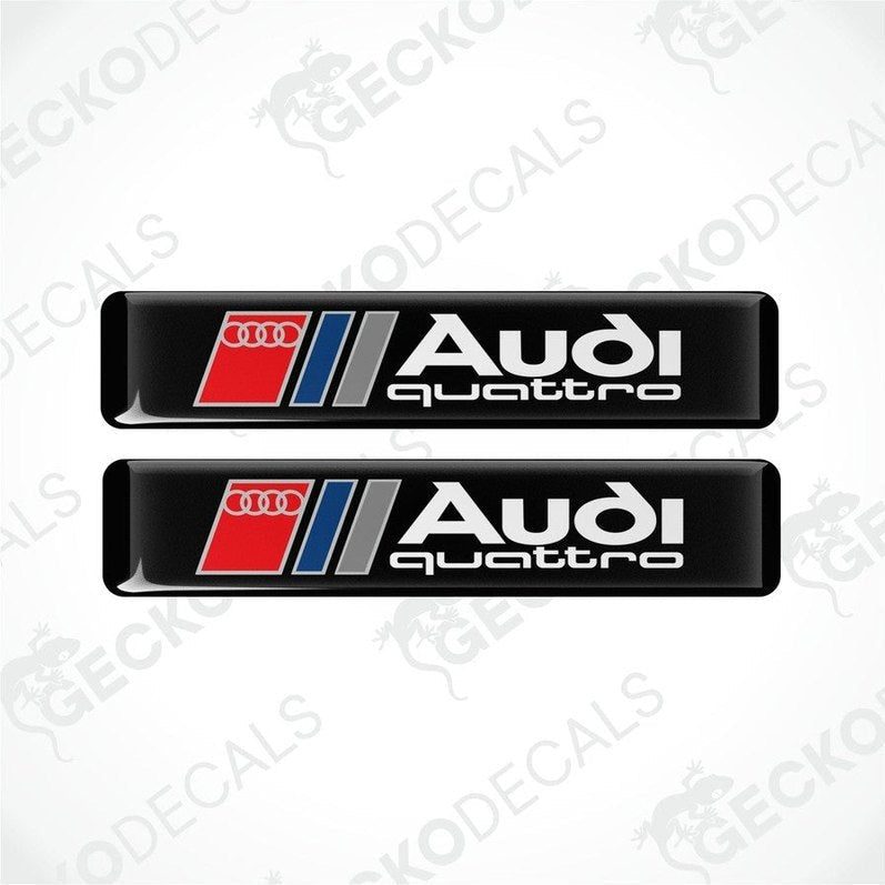 A set of two Audi Quattro branded vinyl decals with a black background and red and silver accents.