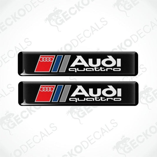 A set of two Audi Quattro branded vinyl decals with a black background and red and silver accents.