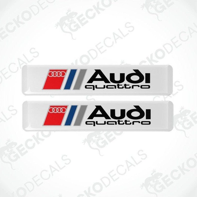 A set of two Audi Quattro branded vinyl decals with a white background and red and silver accents.