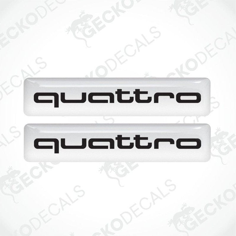 Two white vinyl stickers with the word 'QUATTRO' written in white, placed against a black background.