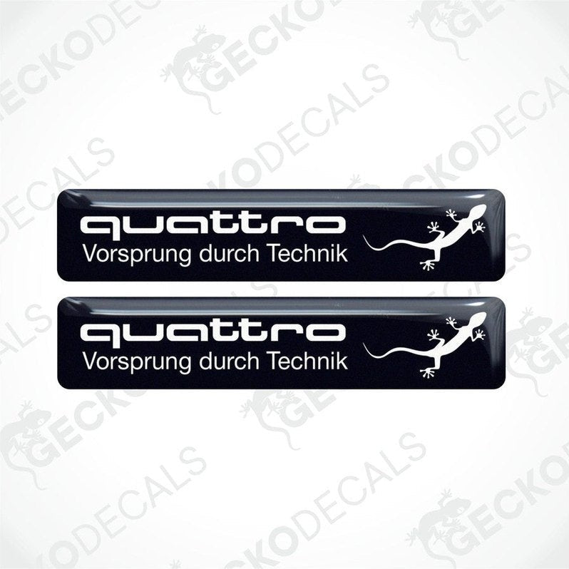 Two black vinyl decals with 'quattro Vorsprung durch Technik' and a white Audi logo on a white background.
