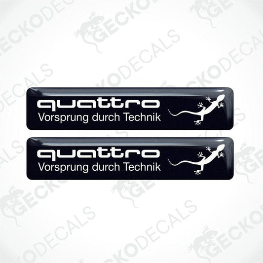 Two black vinyl decals with 'quattro Vorsprung durch Technik' and a white Audi logo on a white background.