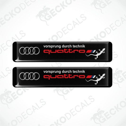 Set of two black vinyl decals with 'quattro' and 'vorsprung durch technik' text, and Audi logo
