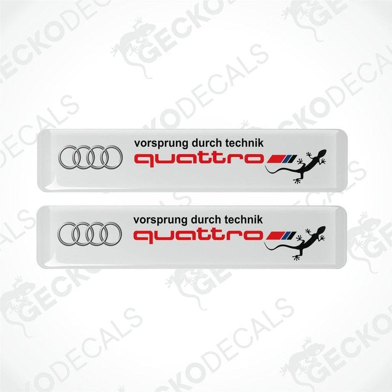 Set of two white vinyl decals with 'quattro' and 'vorsprung durch technik' text, and Audi logo