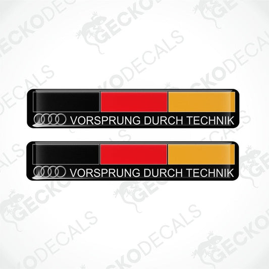 Two rectangular car decals with 'VORSprung DURCH TECHnik' text and the Audi logo, predominantly black with red and yellow stripes.