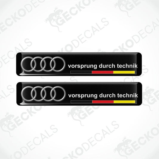 Two black vinyl decals with the text 'vorsprung durch technik' and the Audi logo in silver, arranged horizontally.