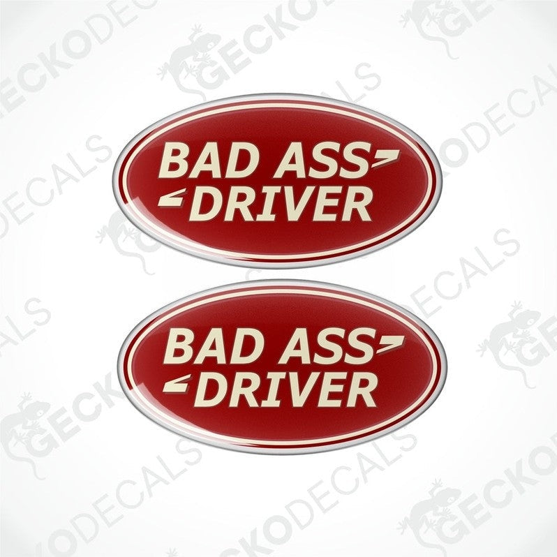 Two red oval-shaped vinyl decals with the text 'BAD ASS DRIVER' in white and silver.

