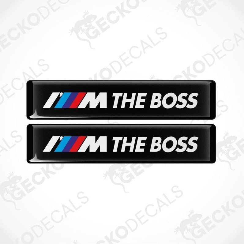Two black rectangular car decals with the text 'THE BOSS' and the BMW logo in white, red, and blue.