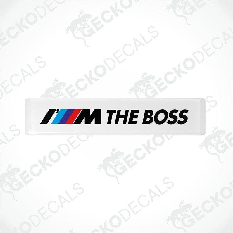 Two withe rectangular car decals with the text 'THE BOSS' and the BMW logo in black, red, and blue.