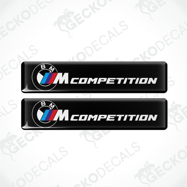 Two black rectangular car decals with 'BMW COMPETITION' text and the BMW logo in white and red.