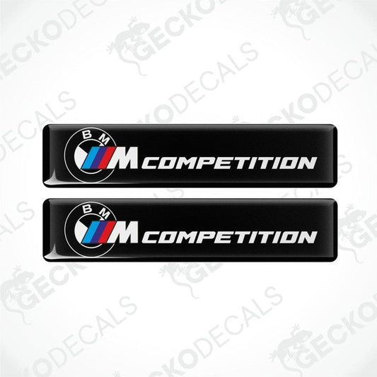 Two black rectangular car decals with 'BMW COMPETITION' text and the BMW logo in white and red.