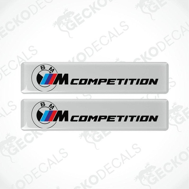 Two white rectangular car decals with 'BMW COMPETITION' text and the BMW logo in black and red.