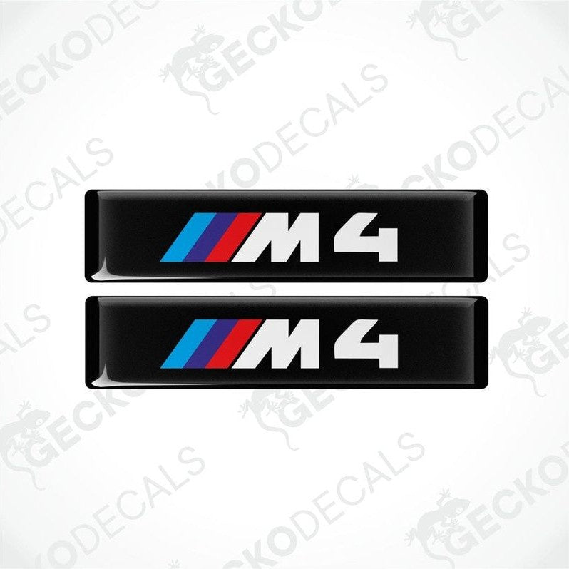 Two stickers with BMW M4 logos in light blue, blue and red on a black background