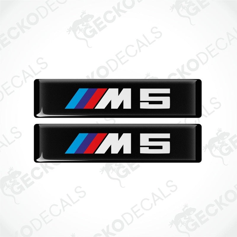 Two stickers with BMW M5 logos in light blue, blue and red on a black background