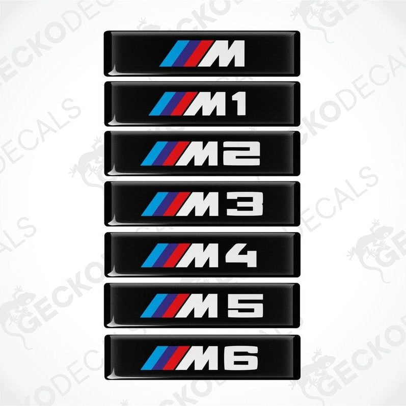 A series of black decals with white and colored text representing different BMW M series models from M1 to M6.
