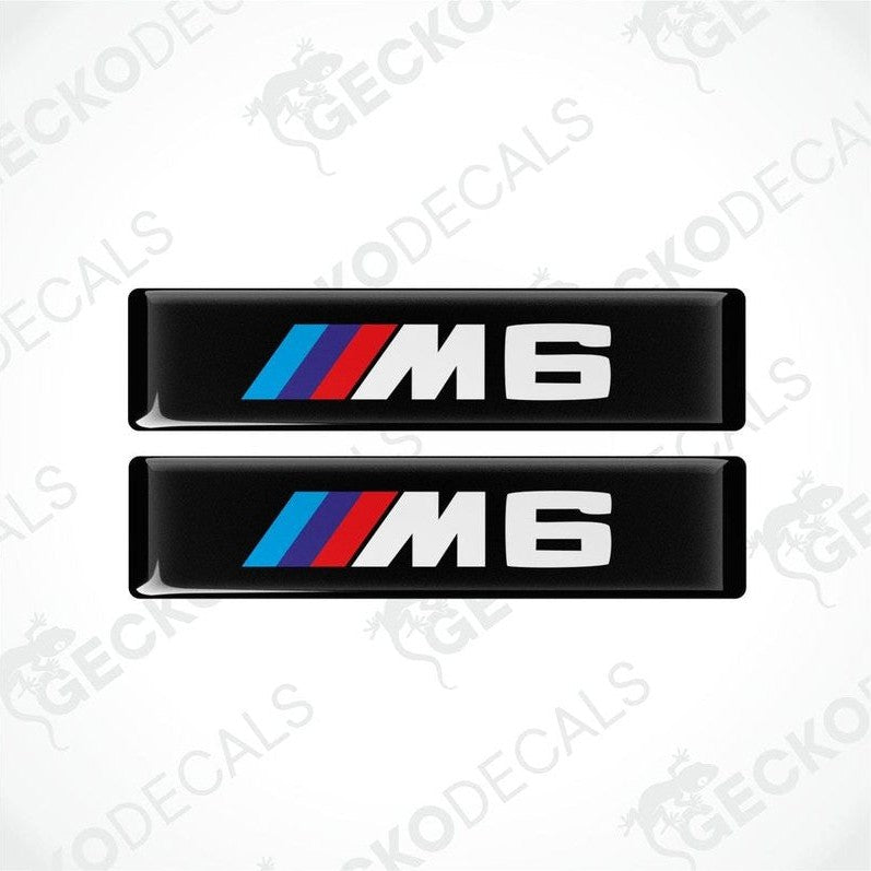 Two stickers with BMW M6 logos in light blue, blue and red on a black background