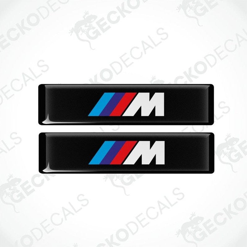 Two stickers with BMW M logos in light blue, blue and red on a black background