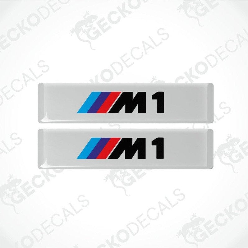 Two stickers with BMW M1 logos in light blue, blue and red on a white background