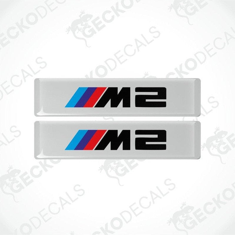 Two stickers with BMW M2 logos in light blue, blue and red on a white background