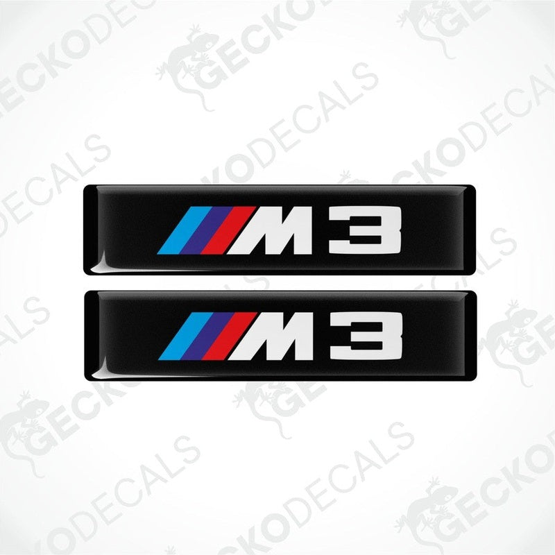Two stickers with BMW M3 logos in light blue, blue and red on a black background