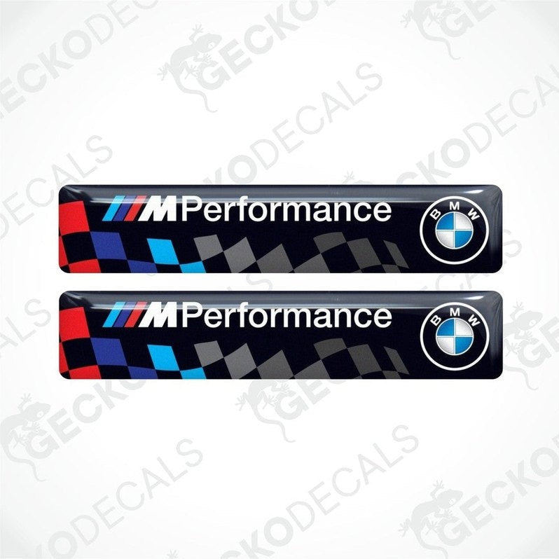 Two vinyl stickers with a BMW M PERFORMANCE logo, predominantly black with blue and red checkered pattern.