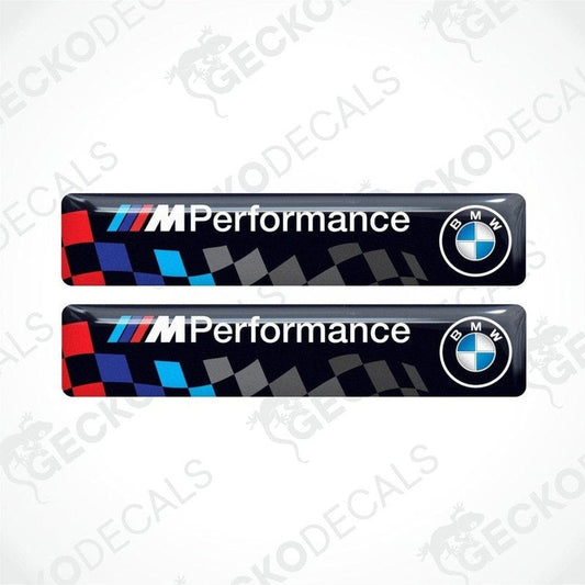 Two vinyl stickers with a BMW M PERFORMANCE logo, predominantly black with blue and red checkered pattern.