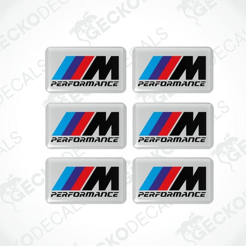 Set of six BMW M Performance vinyl stickers with polyurethane coating featuring the M Performance logo in black, red and blue on a white background.