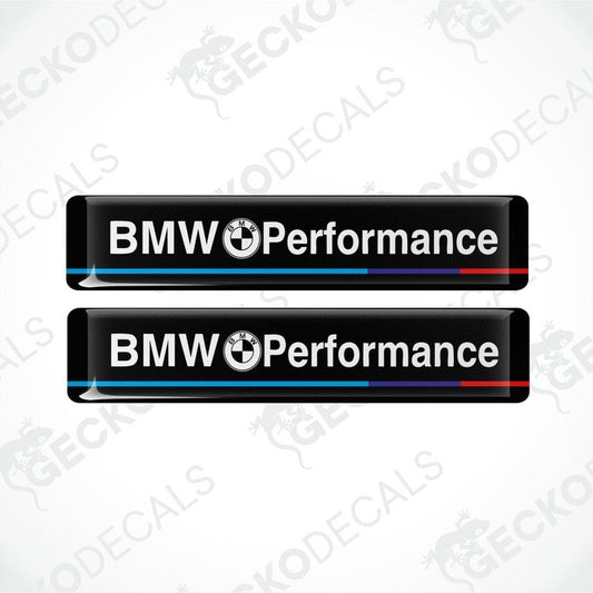 Two rectangular black vinyl decals with 'BMW Performance' text, one with a red stripe and one with a blue stripe.