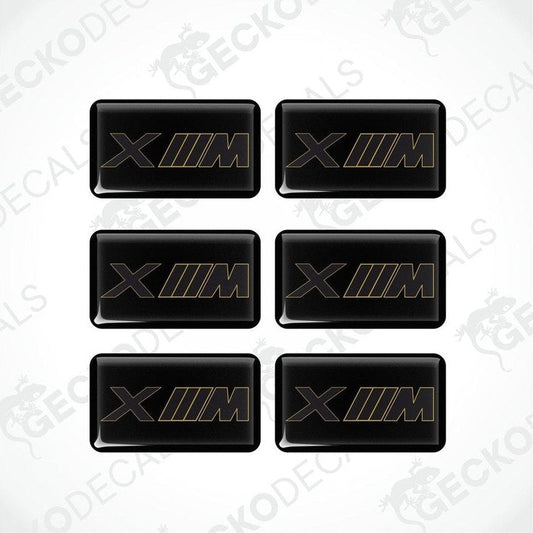A set of six black vinyl stickers with the BMW XM logo in gold.