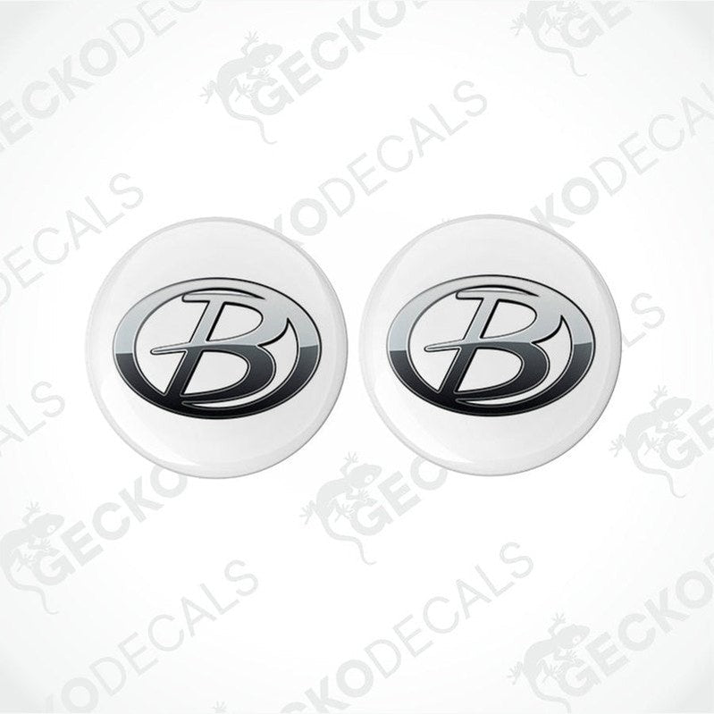 Two round white vehicle decals with a black 'B' logo in the center, placed on a patterned background.