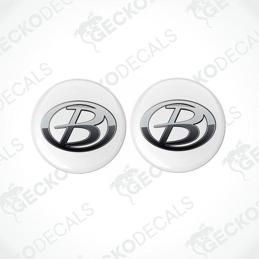 Two round white vehicle decals with a black 'B' logo in the center, placed on a patterned background.